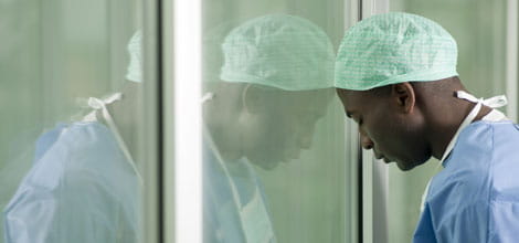Stressed doctor leaning against window